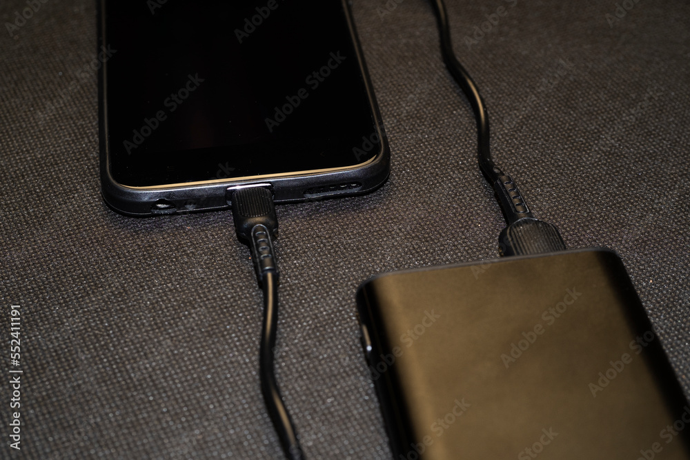 Charging power bank. Portable powerbank with white usb cable for charger mobile phone or smartphone battery. Modern technology concept Charging power bank. Portable powerbank with white usb cable for charger mobile phone or smartphone battery. Modern technology concept