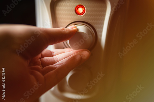 Man adjusting the oil electric heater on at home. Cold winter, economic crisis concept. 