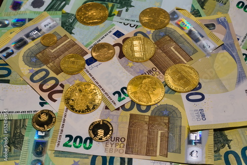Arrangement of crisp 100 EUR and  200 EUR banknotes and gold coins photo