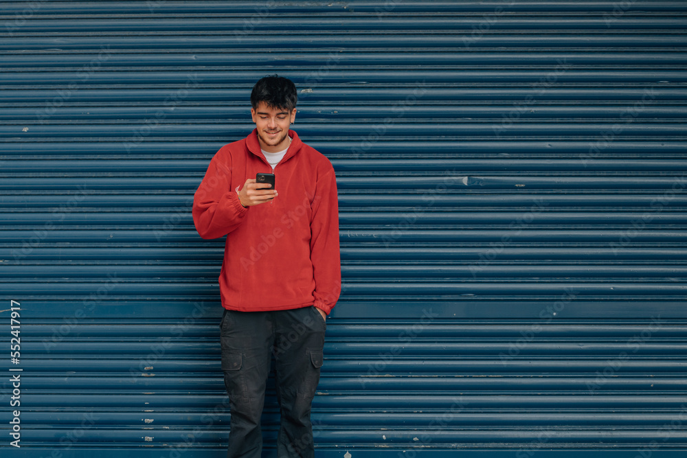 young man with mobile phone in the street with blue background