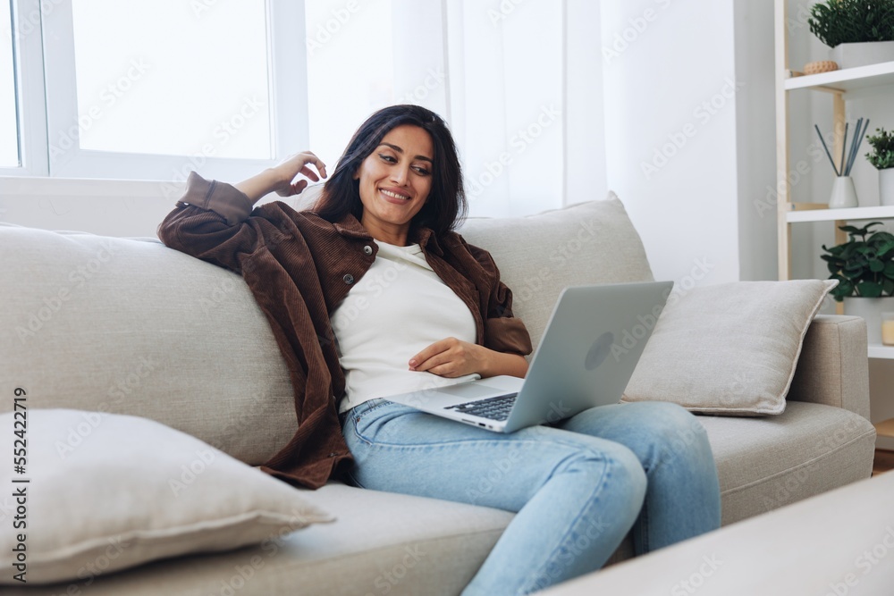 Woman freelancer on day off sitting on sofa with laptop at home online video chat call, smile Woman freelancer on day off sitting on sofa with laptop at home online video chat call, smile