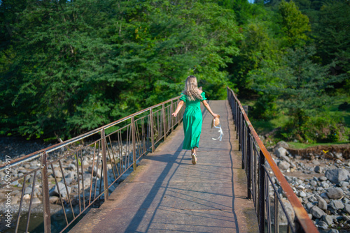 a girl in green walks across the bridge