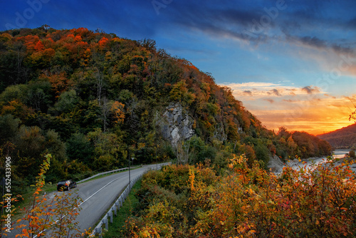 Highway on an autumn day among the mountains under a blue cloudy sky. An asphalt road passes through the mountains on an autumn evening. Landscape in the mountains at sunset.