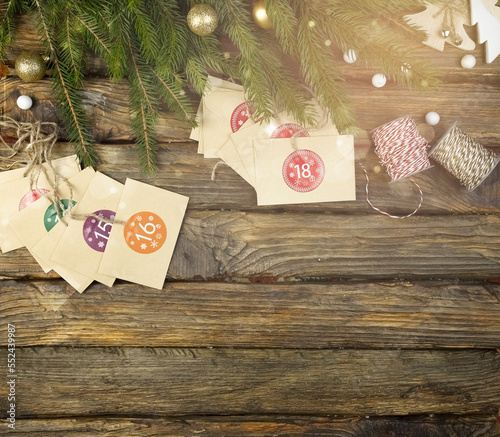 Advent calendar under sprigs of fir on a wooden background with space for a copy. Christmas, festive background with postcards and numbers. Postcard with Advent calendar envelopes