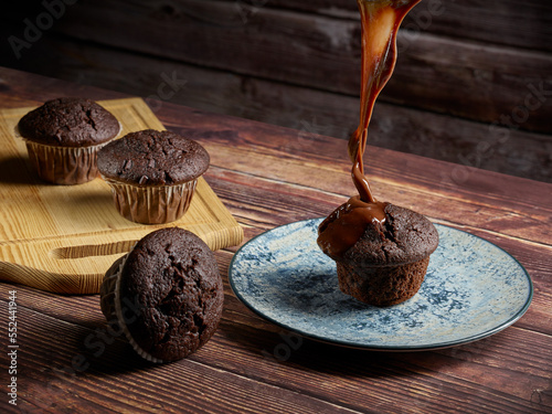 Liquid chocolate falling on chocolate muffins