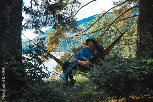 Happy couple man and woman in love resting in a hammock. The lake and Carpathian mountains are in the background. A wonderful warm summer morning, the concept of freedom and travel.