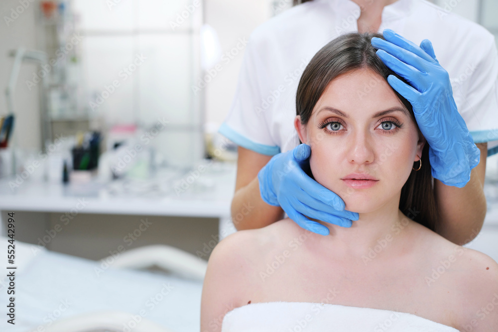 Close up portrait of young blonde woman with cosmetologyst hands in a gloves. Preparation for operation or procedure. Perfect skin, spa and care.