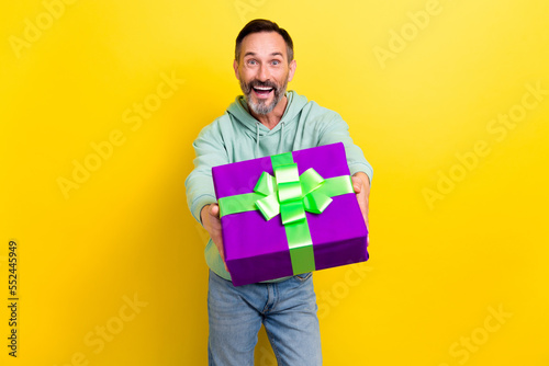 Photo of overjoyed man celebrate event give you present box good mood holiday occasion isolated on yellow color background