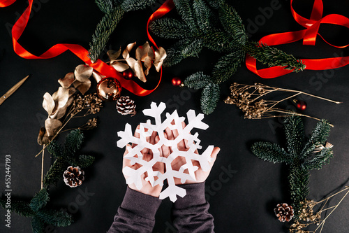 Children holding a white paper snowflake. Making your own Christmas decor. Happy holidays and New year concept.