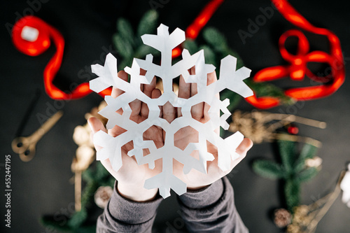 Children holding a white paper snowflake. Making your own Christmas decor. Happy holidays and New year concept.