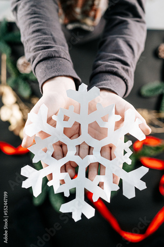 Children holding a white paper snowflake. Making your own Christmas decor. Happy holidays and New year concept.