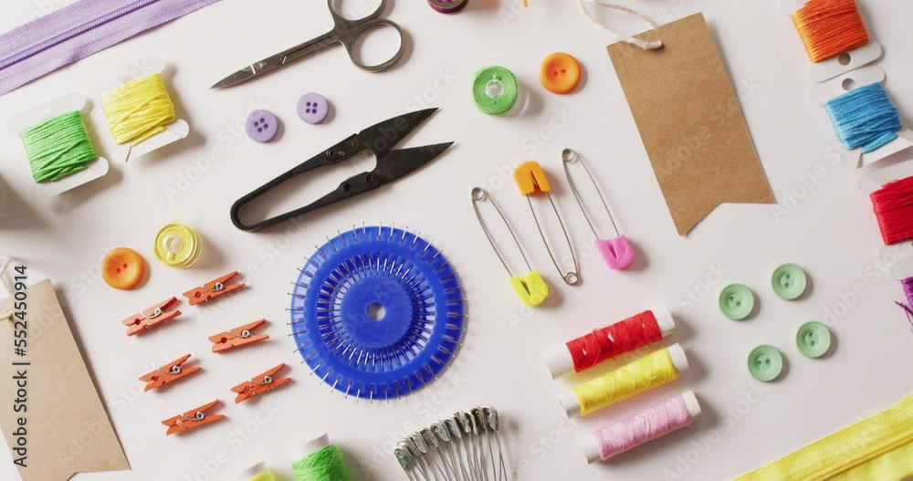 Video of dressmaking scissors, pins, buttons and threads arranged on white background