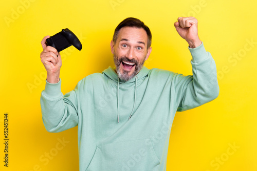 Portrait of positive overjoyed man champion raise hand fist rejoice good mood done finish playstation isolated on yellow color background