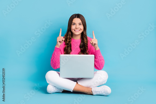 Full length photo of sweet dreamy girl dressed knit pullover rising typing gadget looking pointing up empty space isolated blue color background © deagreez