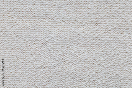 Close-up texture of handmade knitted woolen fabric in beige, ivory, cream color. Textile background, top view, copy space