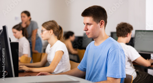 Teenage caucasian boy learning to use personal computer during lesson in school.