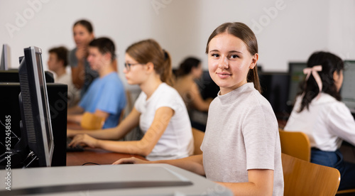 Excited female teenager learning computer science while she is using a PC in the computer classroom
