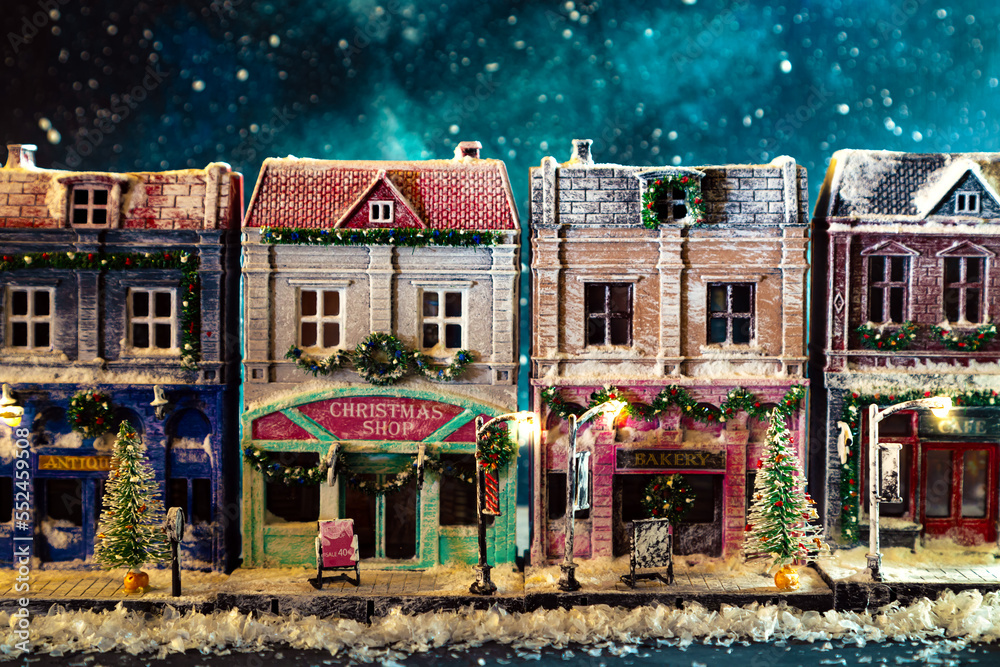 Night snow-covered European street decorated for Christmas. Homemade decorated toy houses.