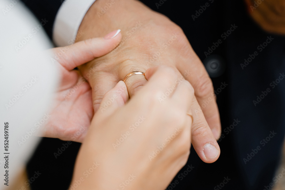 bride puts gold wedding ring on groom's finger bride puts gold wedding ring on groom's finger