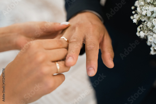bride puts gold wedding ring on groom s finger