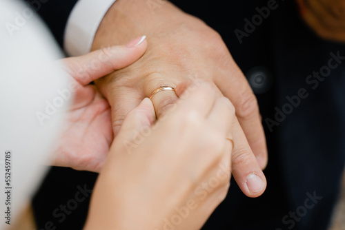 bride puts gold wedding ring on groom's finger