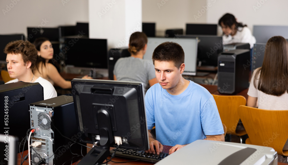 Fototapeta premium Concentrated schoolboy working with computers in classroom