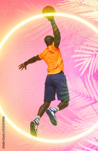 Rear view of african american basketball player taking a shot with ball over circle and plants