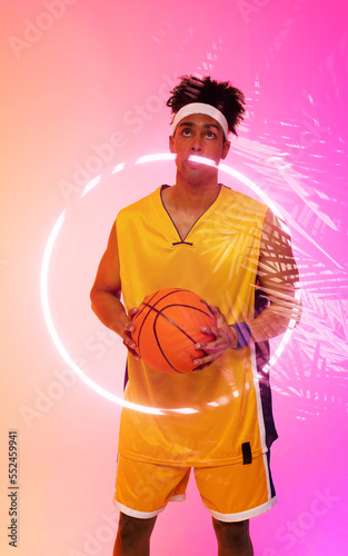 Composite of biracial basketball player holding ball looking up while standing by circle and plants