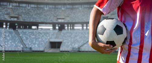 Fototapeta Naklejka Na Ścianę i Meble -  Midsection of player holding soccer ball in stadium, copy space