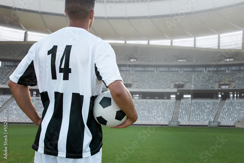 Rear view of number 14 player with soccer ball in stadium, copy space