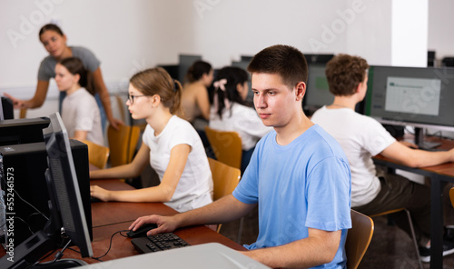 Modern boy student learning basics of programming in group course in computer college © JackF