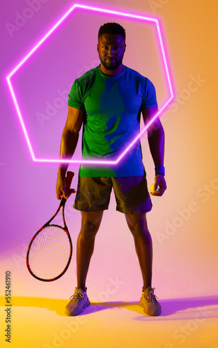 Hexagon neon over confident african american tennis player with racket against colored background