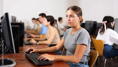 Focused female teenager solving tasks of computer science in the auditory © JackF