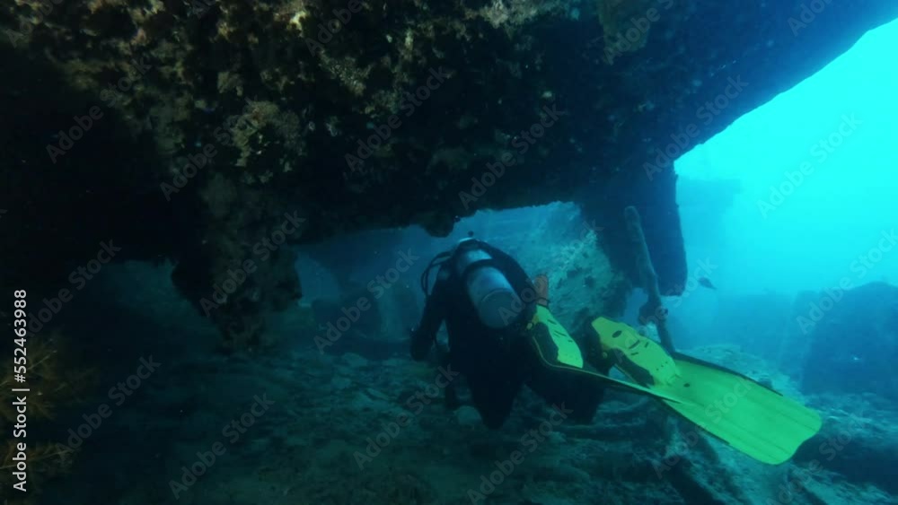 Diver exploring sunken ship underwater, shining with flashlight, back view tracking shot. Ocean bottom scuba diving, old vessel wreck undersea Diver exploring sunken ship underwater, shining with flashlight, back view tracking shot. Ocean bottom scuba diving, old vessel wreck undersea