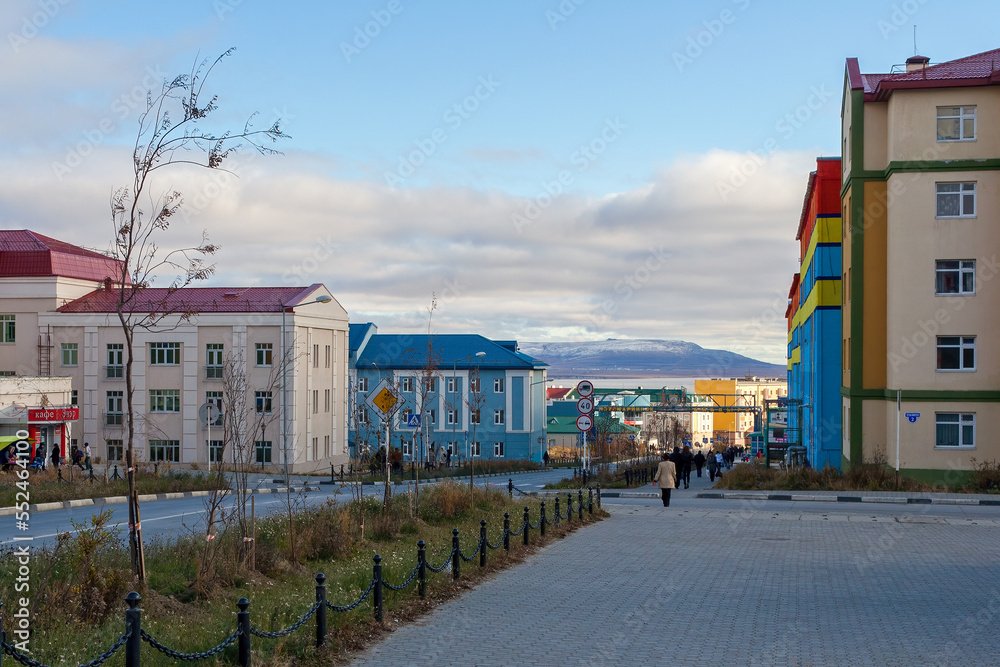 Anadyr, Chukotka, Russia. Autumn view of the street of a well-maintained northern city located in the Arctic. People walk along the sidewalk past colorful buildings.