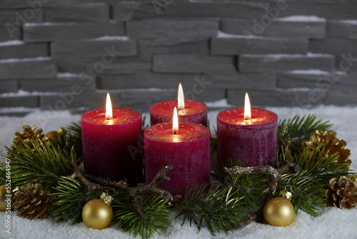 Adventskranz mit vier brennenden roten Kerzen zum vierten Advent.