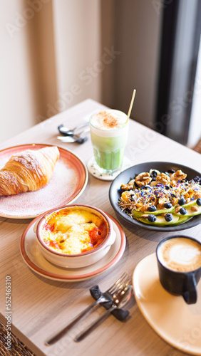 breakfast in a coffee shop with a matcha latte and fruit bowl, a croissant and shakshuka