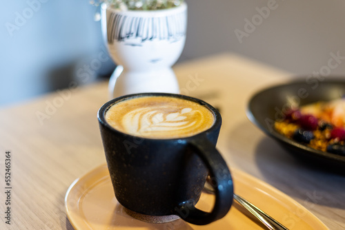cup of flat white with a tulip art latte, cup of black ceramic