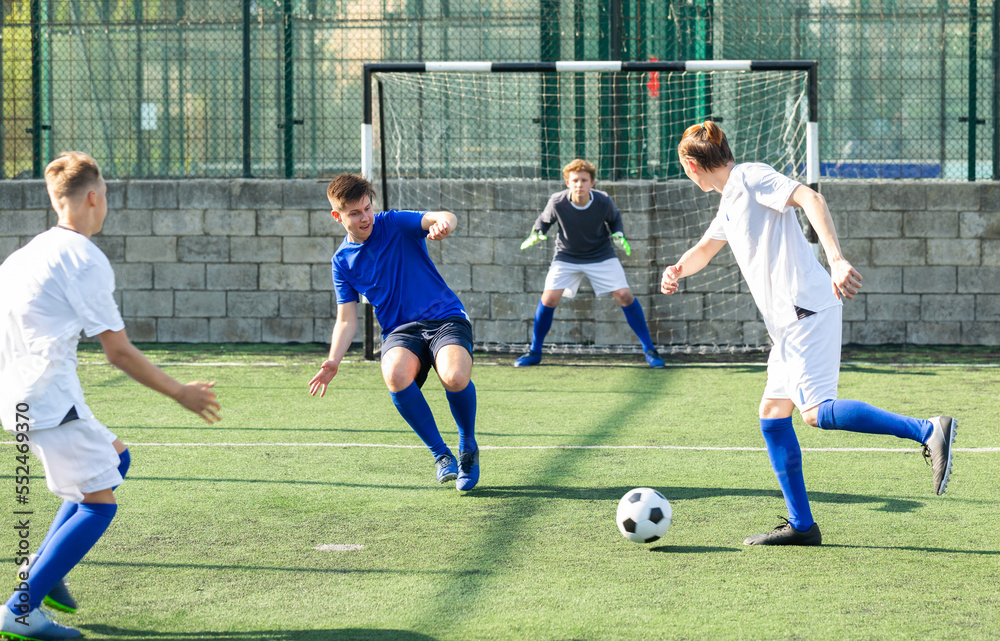 Fototapeta premium Young football players fighting for ball in middle of field