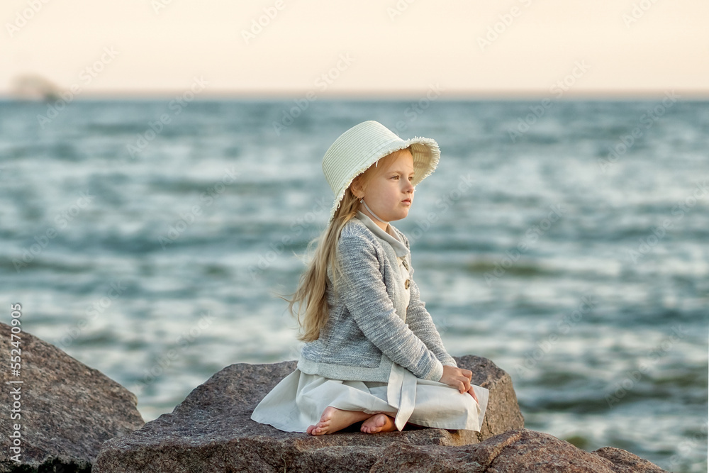 girl in a hat sitting on the beach