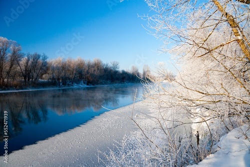 Photo the snow-covered river did not freeze in winter.The river flows in winter. Snow on the branches of trees. Reflection of snow in the river. Huge snowdrifts lie on the Bank of the stream. © Oleksandr Smushko