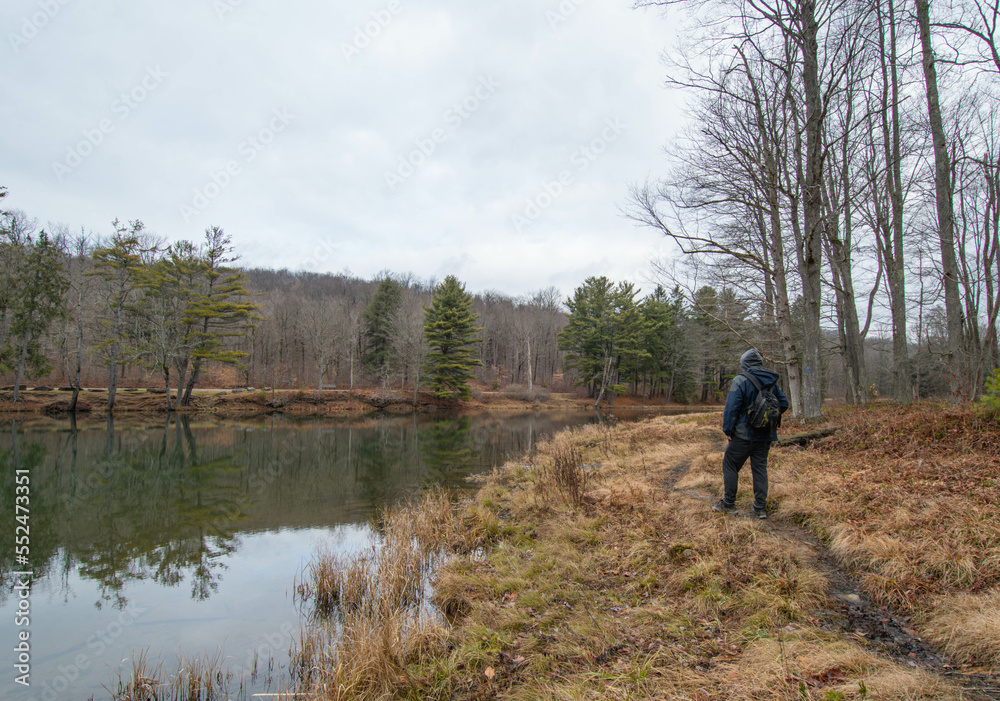 Hiker standing by lakes shore right after fresh snow fall, travel adventure theme.