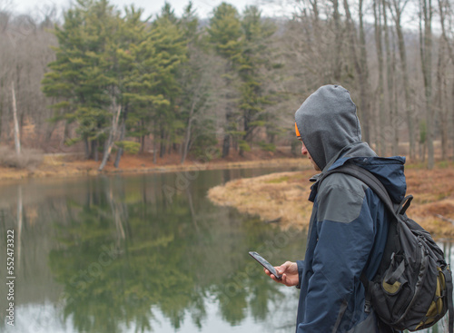 Hiker standing by lakes shore right after fresh snow fall, travel adventure theme.