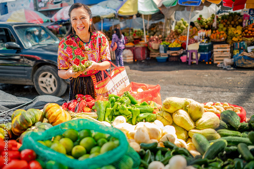 Mujer comprando en un puesto de frutas y verduras en un mercado local de Guatemala.