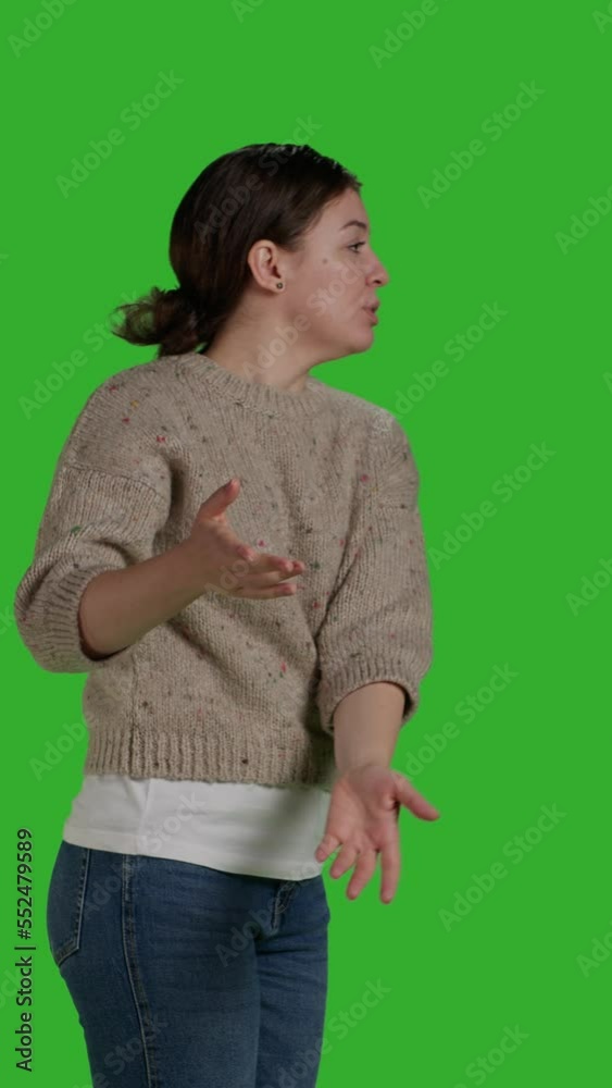 Vertical video: Profile close up of adult showing something aside in studio, doing advertisement and presentation in front of camera. Confident woman pointing sideways to create ad or example on