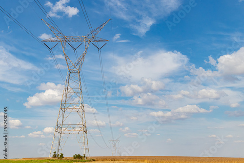 Electricity transmission towers in rural farm field. Electrical power grid and distribution safety, security and maintenance concept photo
