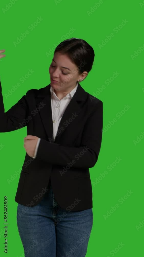 Vertical video: Front view of professional manager pointing aside to show advertisement over greenscreen studio backdrop, creating example ad on blank copyspace. Young adult with suit showing ad icon Vertical video: Front view of professional manager pointing aside to show advertisement over greenscreen studio backdrop, creating example ad on blank copyspace. Young adult with suit showing ad icon