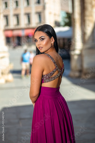 Beautiful young woman in a long dress enjoys a walk in the old part of the city
