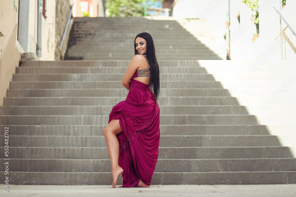 Beautiful black woman in a long red pink dress is walking