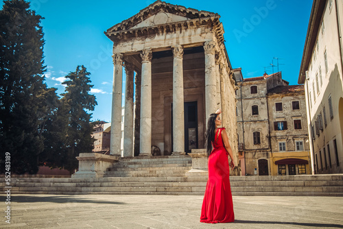 Beautiful young woman stands next to an old monument
